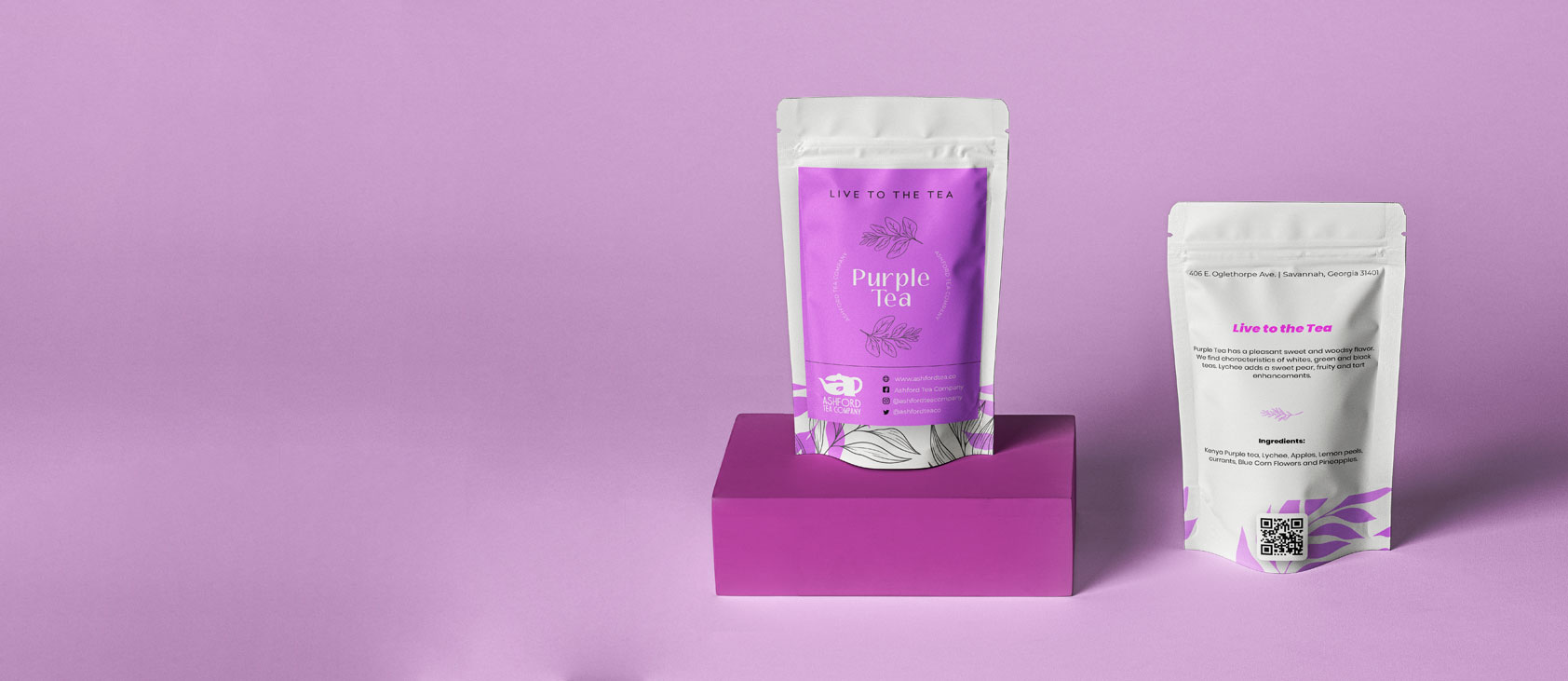 Paquete de té morado de Ashford Tea Company sobre fondo rosa, destacando el diseño moderno y atractivo de la marca, con información sobre ingredientes y el lema "Live to the Tea".