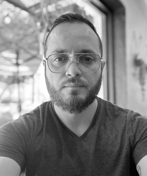 Hombre con gafas y barba, posando en un entorno de oficina, reflejando el enfoque profesional de Blue Edge Business Solutions en marketing digital y estrategias de redes sociales.