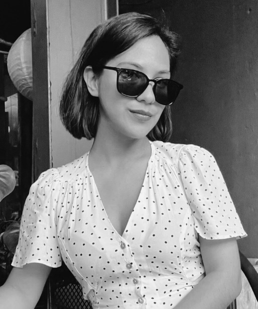 Mujer sonriendo con gafas de sol, vestida con blusa blanca con lunares, en un entorno que sugiere creatividad y profesionalismo, representando el enfoque de Blue Edge Business Solutions en marketing y diseño.